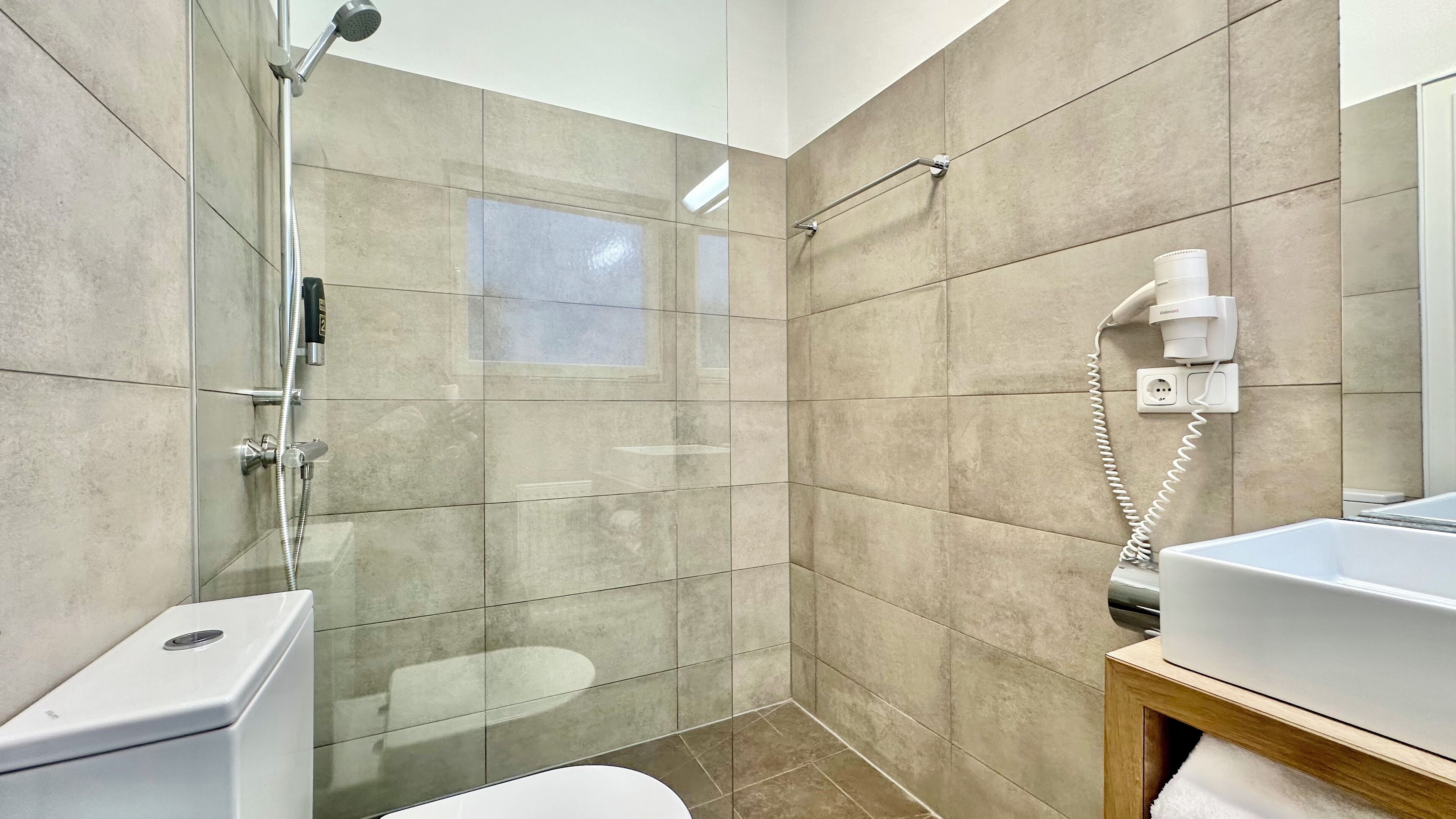 A modern bathroom with a glass-enclosed shower, a toilet, and a sink.