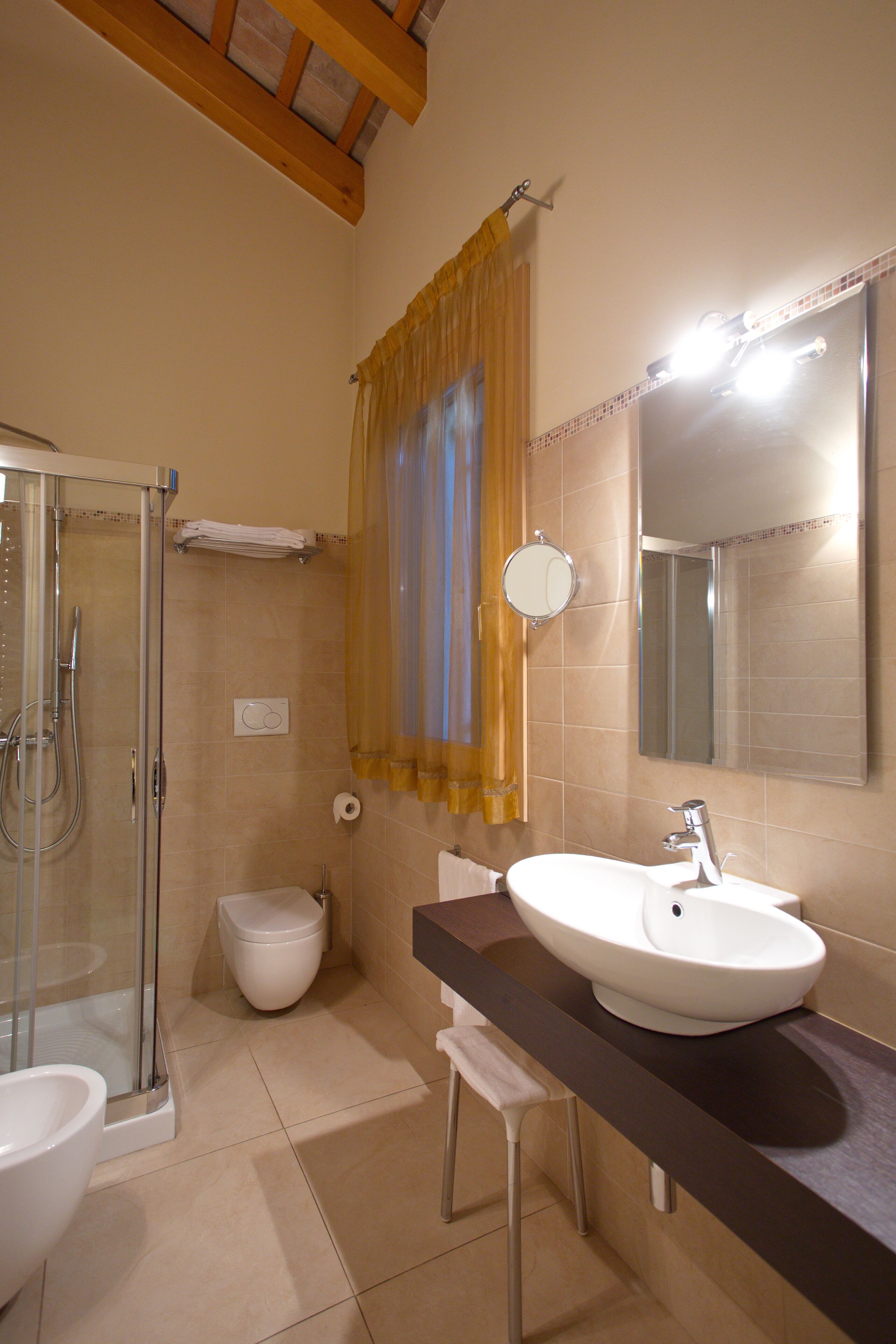 A bathroom with a glass shower enclosure, a toilet, a sink with a mirror, and a towel rack.