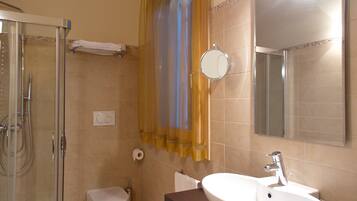 A bathroom with a glass shower enclosure, a toilet, a sink with a mirror, and a towel rack.