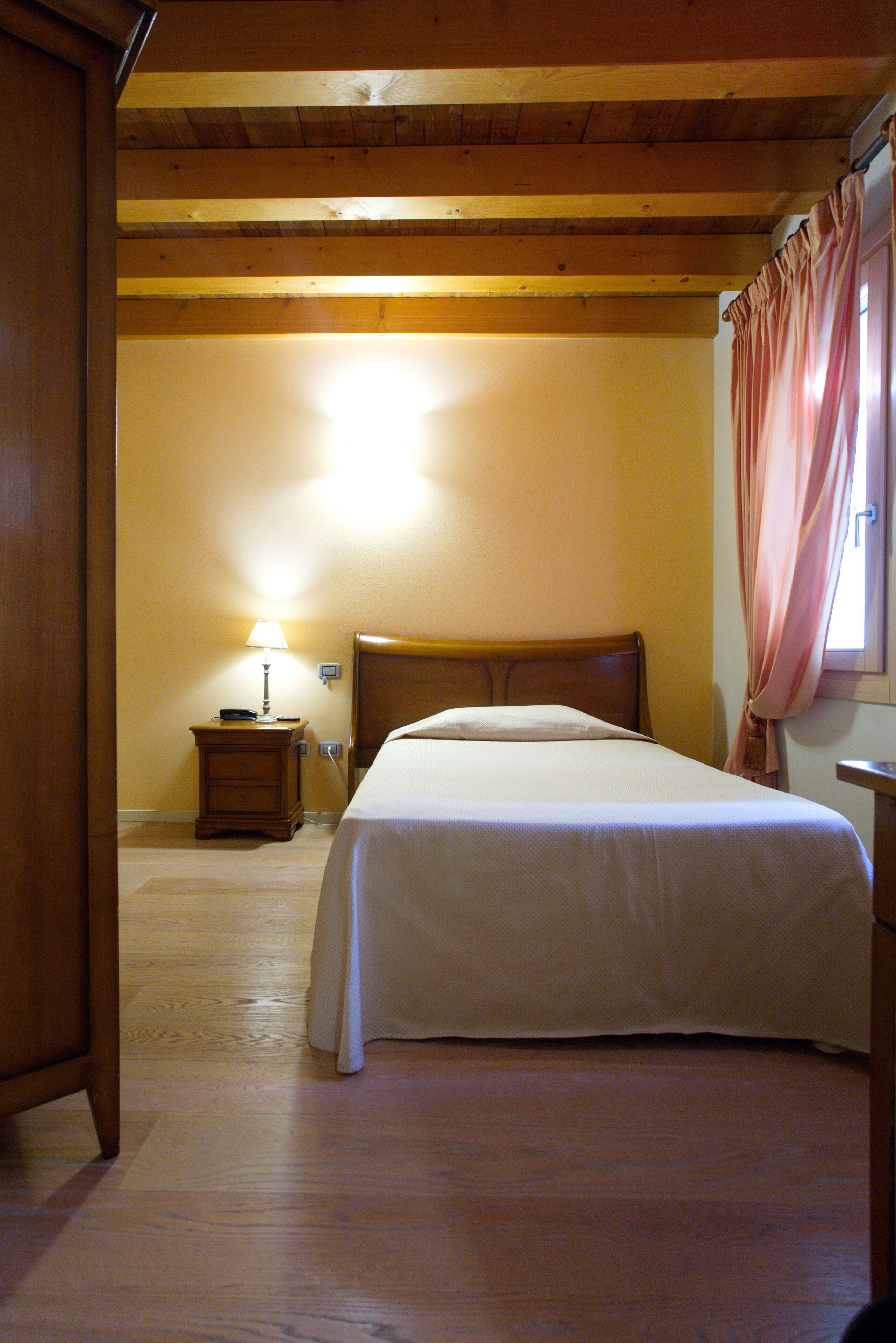 Une chambre à coucher avec un lit en bois, une table de chevet avec une lampe et une fenêtre avec des rideaux.
