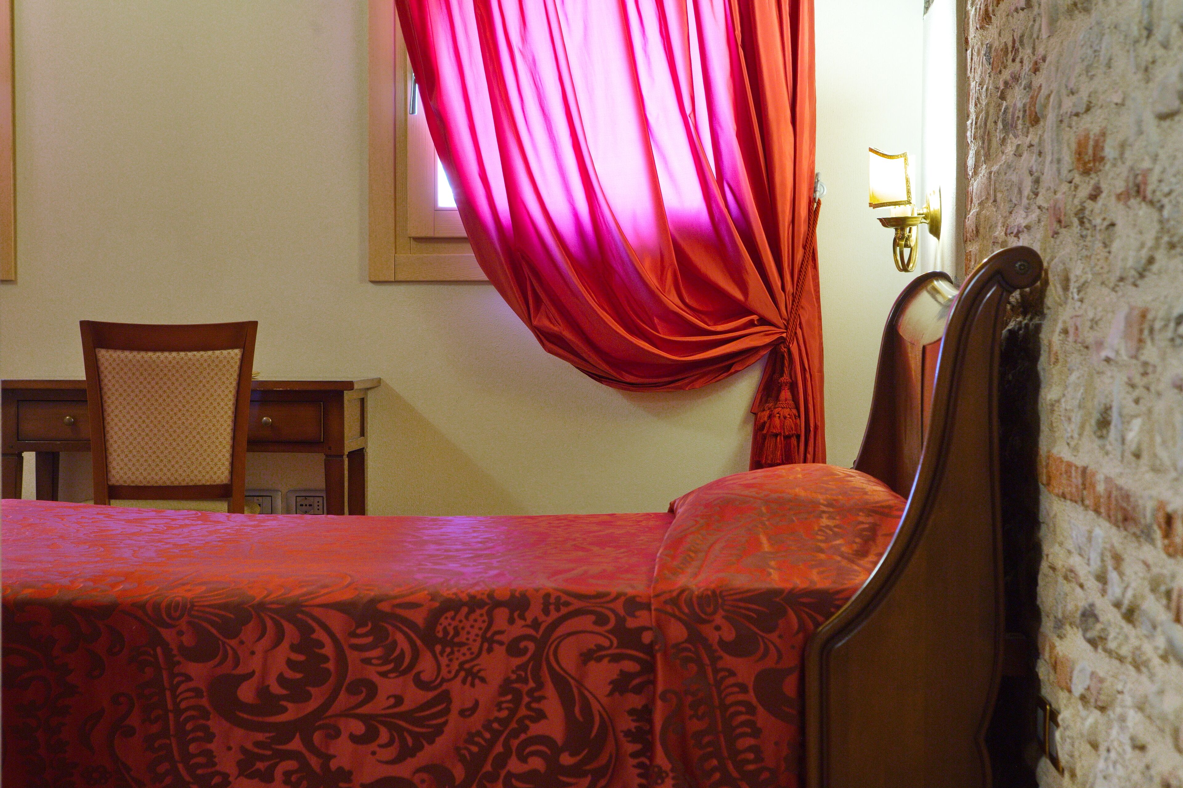 A room with a bed, a chair, a desk, and a wall with a textured surface.