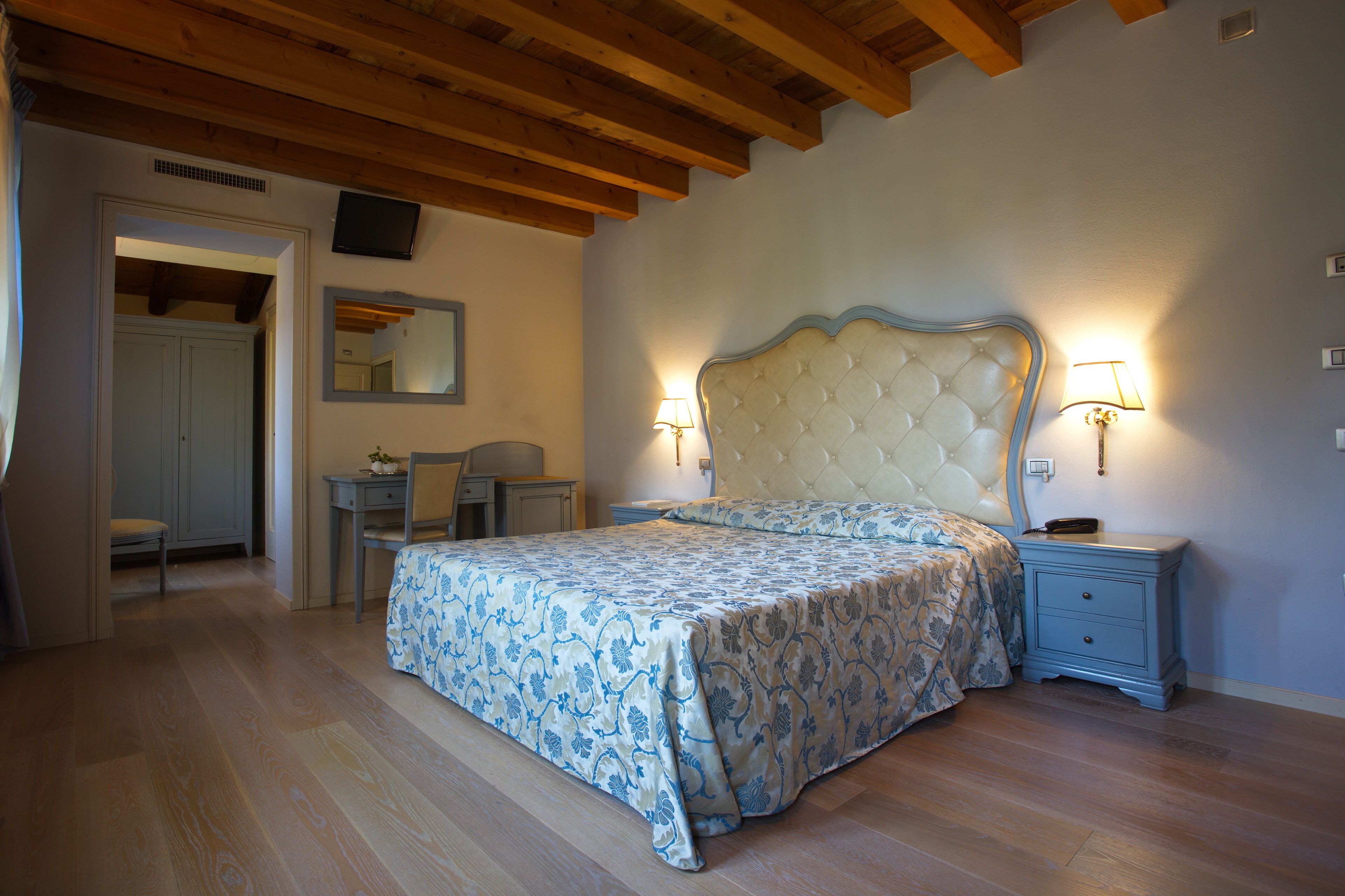 Une chambre à coucher avec un grand lit, des lampes de chevet, un petit bureau et une chaise.