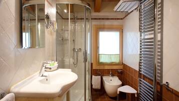 Een badkamer met een douche met glazen wand, een wastafel, een toilet en een handdoekrek.