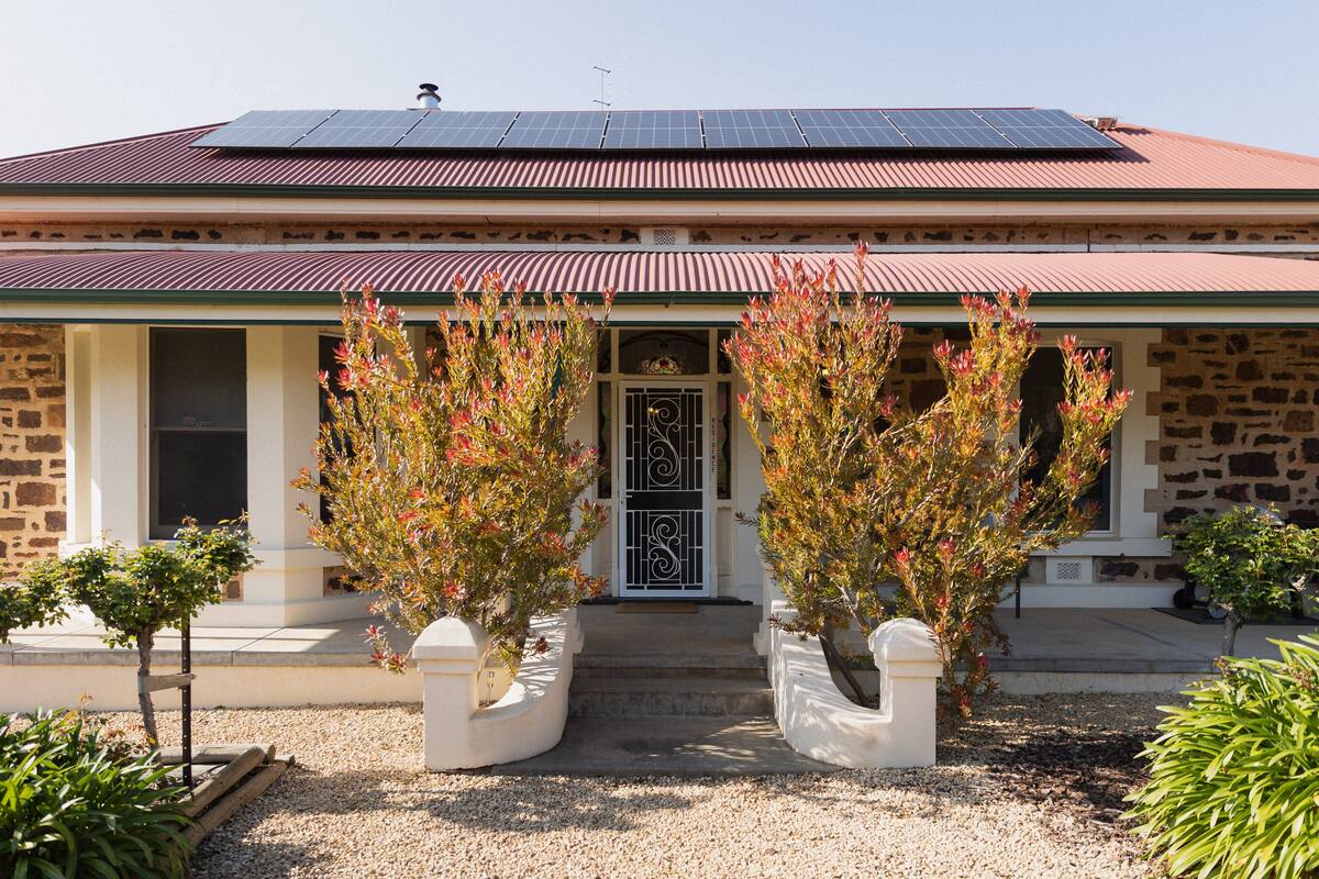 A building with a stone facade, a red roof, and solar panels.