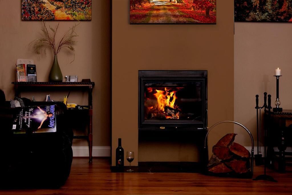A cozy living room with a fireplace, a bookshelf, and a decorative vase.