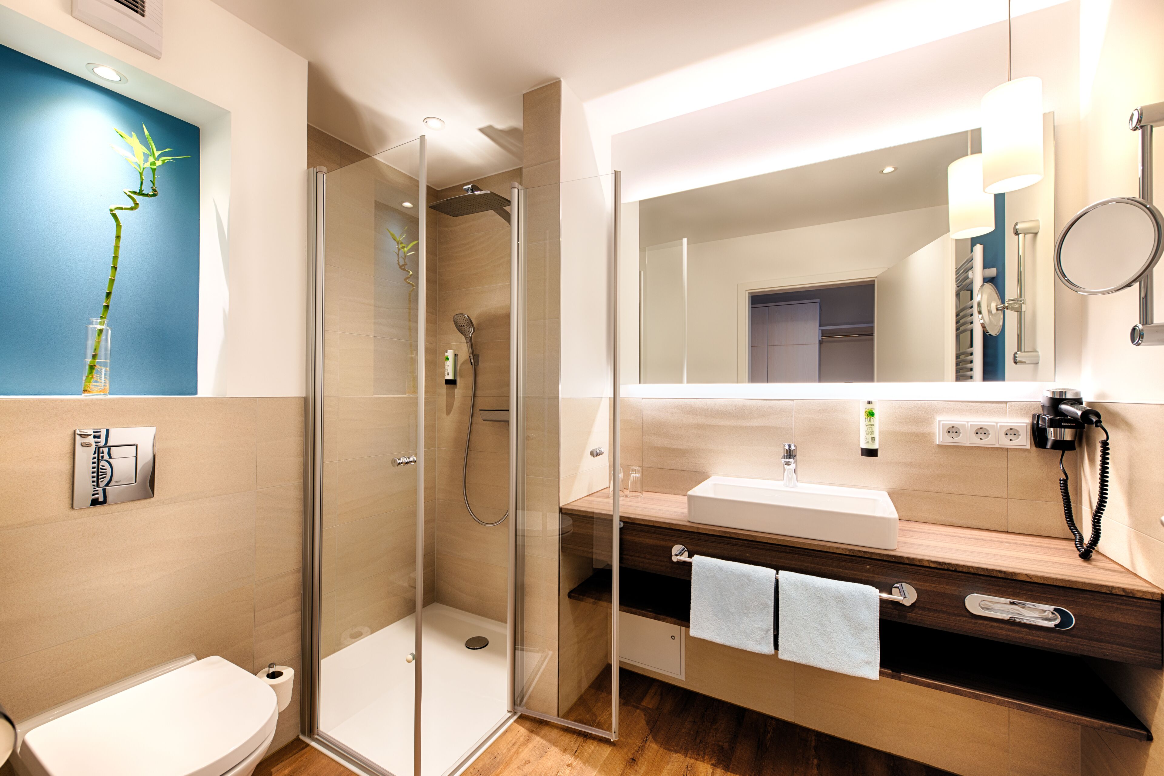 A modern bathroom with a glass-enclosed shower, a wooden vanity with a mirror, and a toilet.