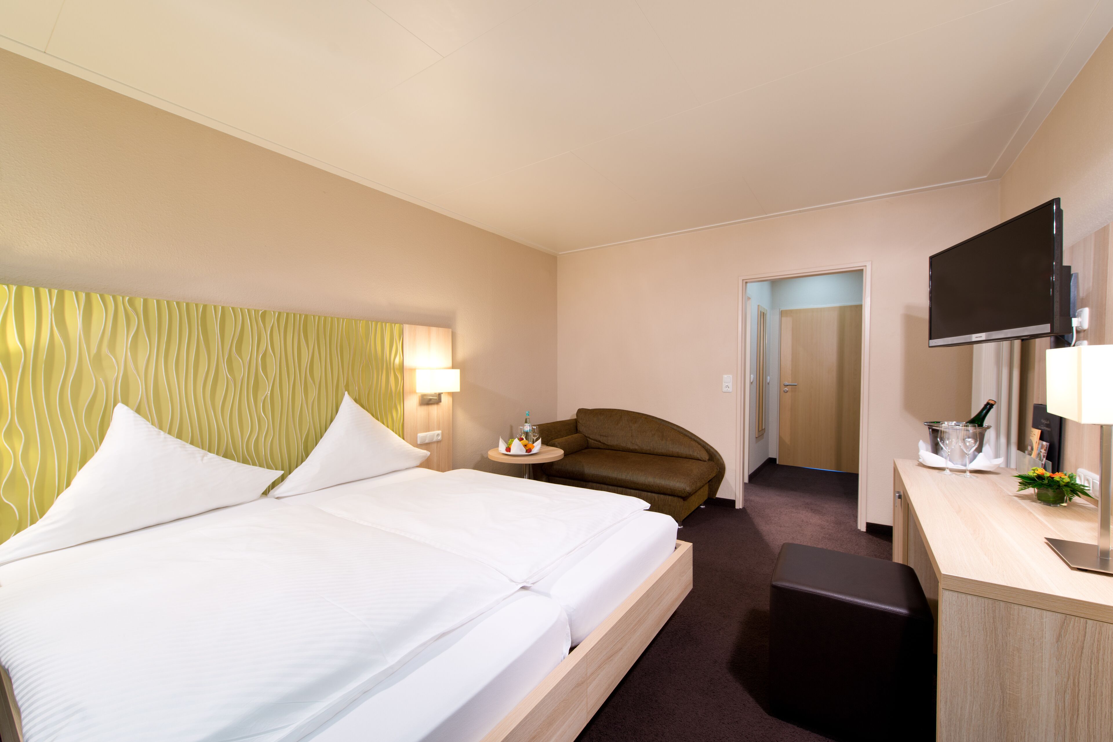 Habitación de hotel con cama, escritorio, televisor y una silla.