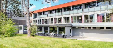 Un edificio moderno con techo plano, ventanas amplias y asientos al aire libre.
