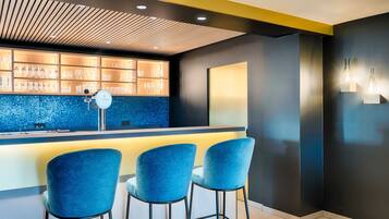 A bar area with a blue tiled backsplash, a wooden ceiling, and three blue bar stools.