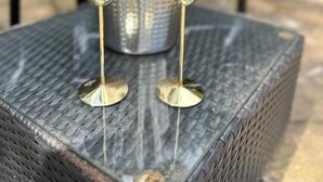 To guldglas på et struktureret metalbord med en metalbeholder i midten.