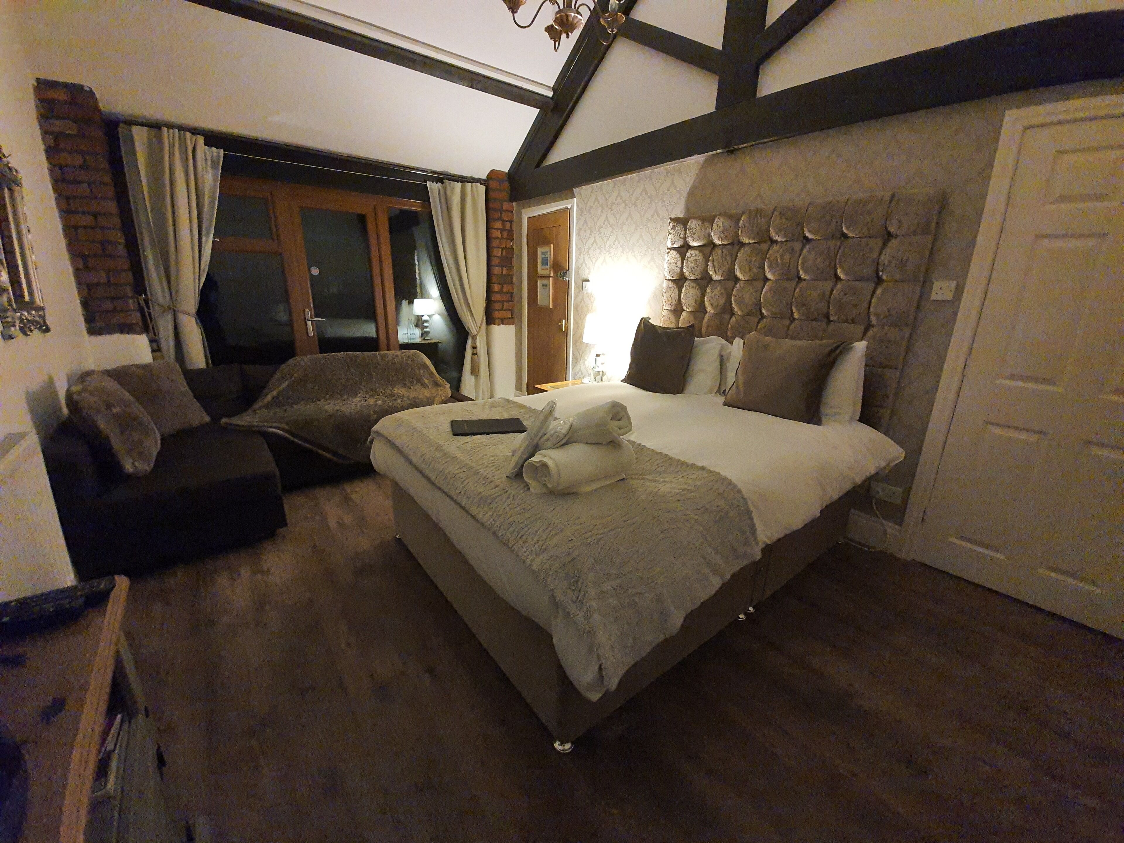 A bedroom with a large bed, a sofa, and a window with curtains.