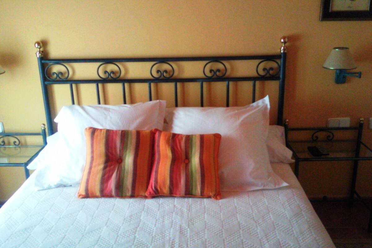 A bed with white bedding, a striped pillow, and a metal headboard.