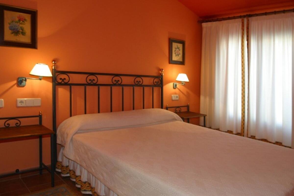 A bedroom with a bed, two bedside tables, and two wall-mounted lamps.