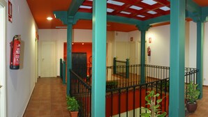 Ein mehrgeschossiges Interieur mit rotem und türkisfarbenem Farbschema, einer Treppe mit schwarzen Geländern und an den Wänden angebrachten Feuerlöschern.