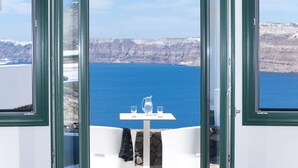 Una mesa con una jarrón y vasos, con vistas a un acantilado y al mar.