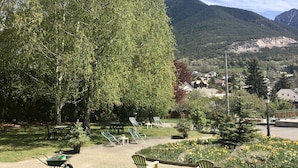 Un parc avec une pelouse verdoyante, des arbres et un parterre de fleurs.
