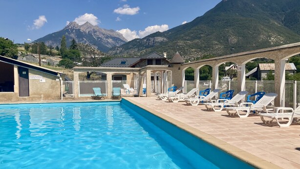 Un espace piscine avec des chaises longues et une vue imprenable sur les montagnes.