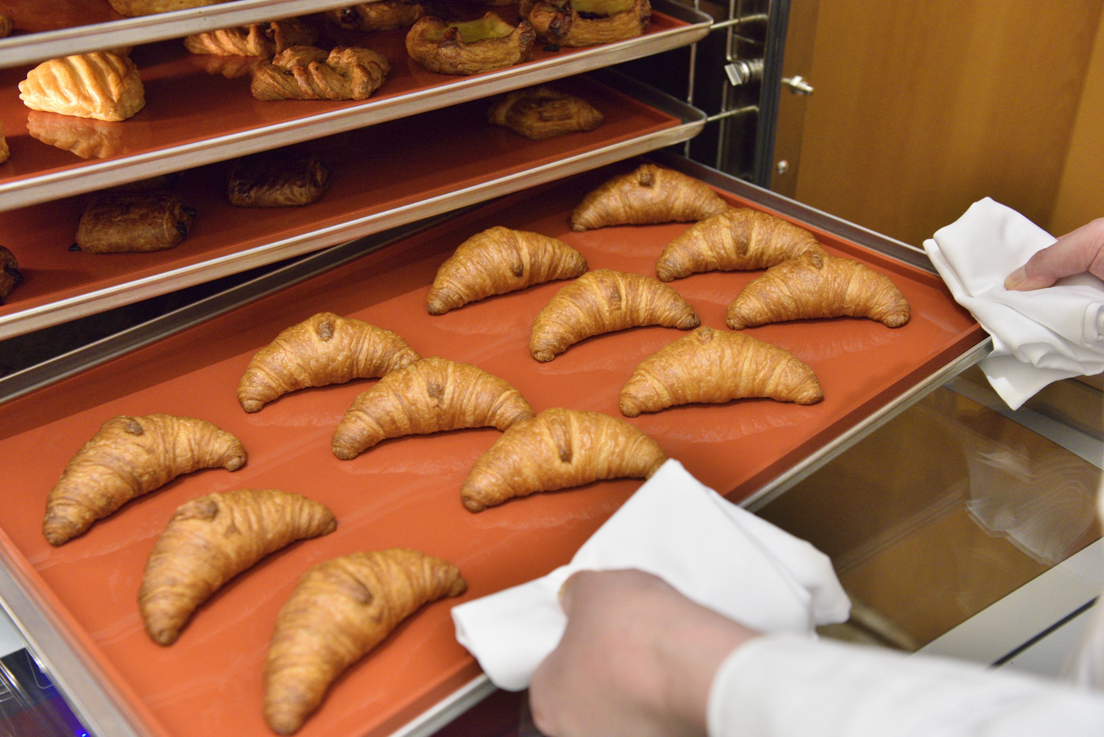 Una vitrina de panadería con cruasanes en bandejas.