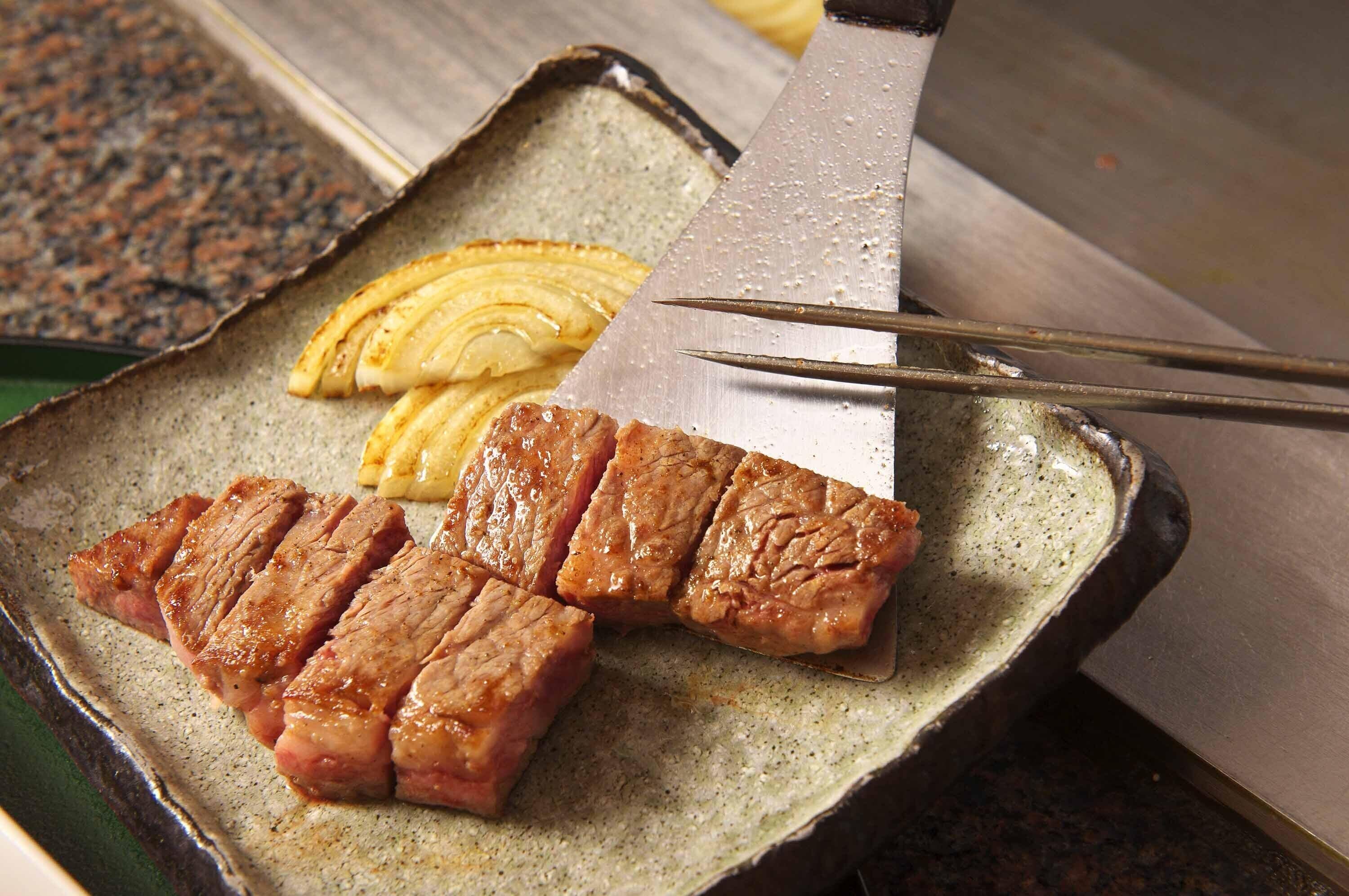 A ceramic plate with sliced meat and onions.