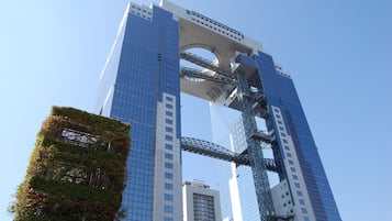A modern high-rise building with a distinctive arched bridge structure connecting two towers.
