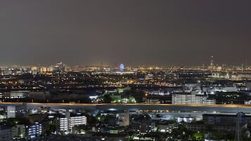 Un paisaje urbano nocturno con edificios iluminados, una noria y un puente.