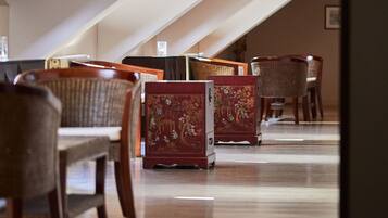 A spacious room with a sloped ceiling, wooden flooring, and traditional furniture including chairs and a cabinet.