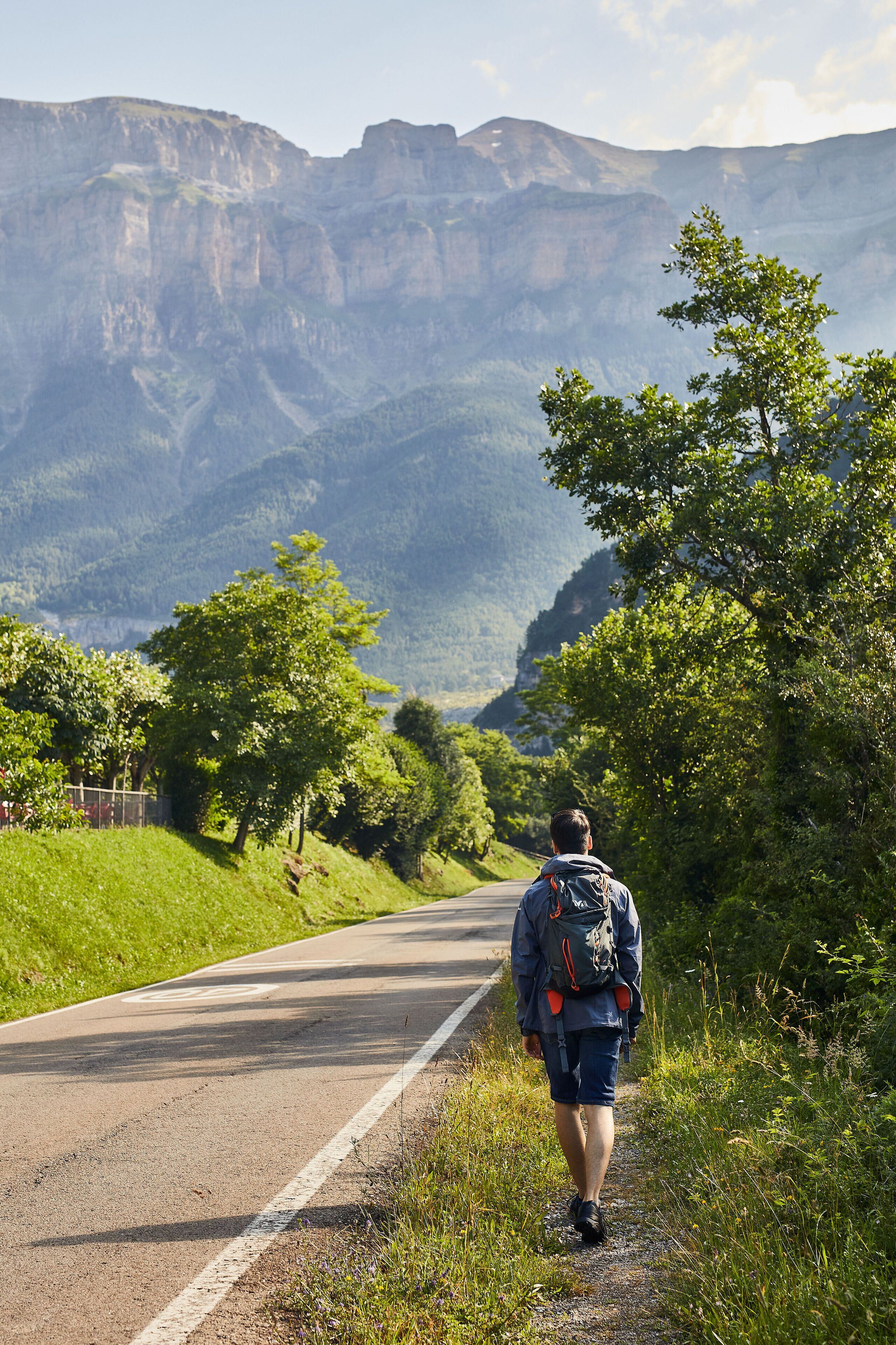A person walking on a road with a mountainous landscape in the background.