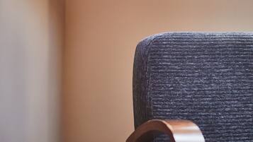 Rincón de una habitación con techo de madera y sillón tapizado oscuro.