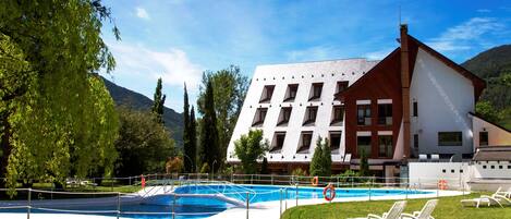 Un hotel con piscina, rodeado de exuberante vegetación y montañas.