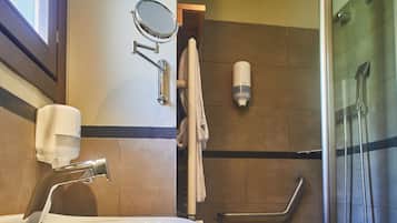 Ein Badezimmer mit Waschbecken, Spiegel, Seifenspender und Duschbereich.