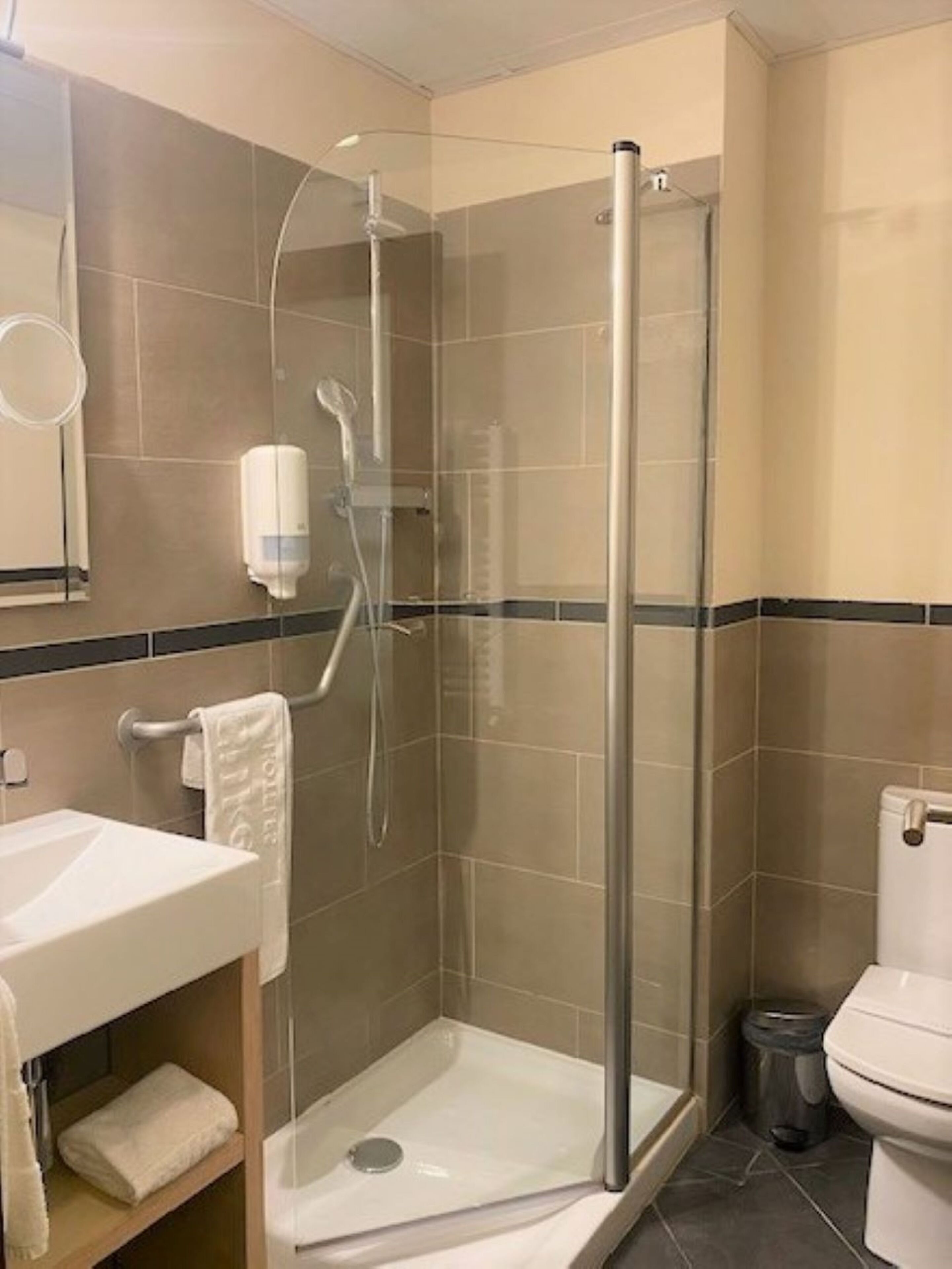 Una doccia con porta in vetro, un lavandino bianco e un water.