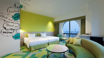 A hotel room with a bed, a sofa, a round table, and a large window with a city view.