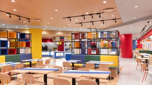 A brightly lit indoor space with multiple tables and chairs, featuring colorful storage units and a modern ceiling design. - Hotel Kintetsu Universal City (Osaka)