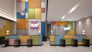 A reception area with two counters, each with a neon sign, and a colorful wall design. - Hotel Kintetsu Universal City (Osaka)