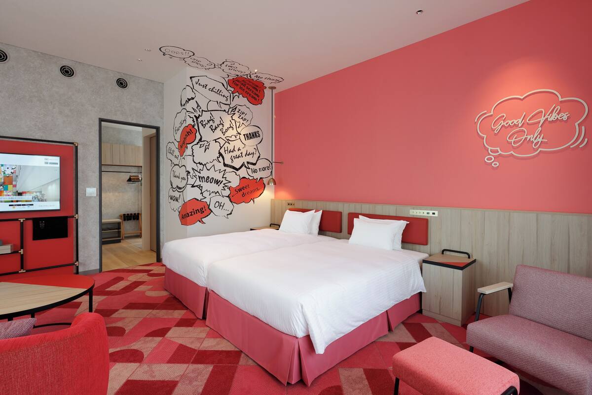 Una habitación de hotel moderna con una cama grande, televisión y una decoración en tonos rojo y blanco.