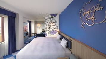 A hotel room with a large bed, a desk, and a wall with a 'Good Vibes Only' sign.