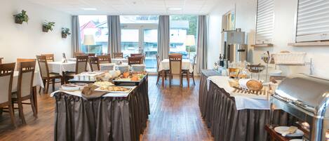 A dining area with multiple tables, a buffet setup, and a coffee station.