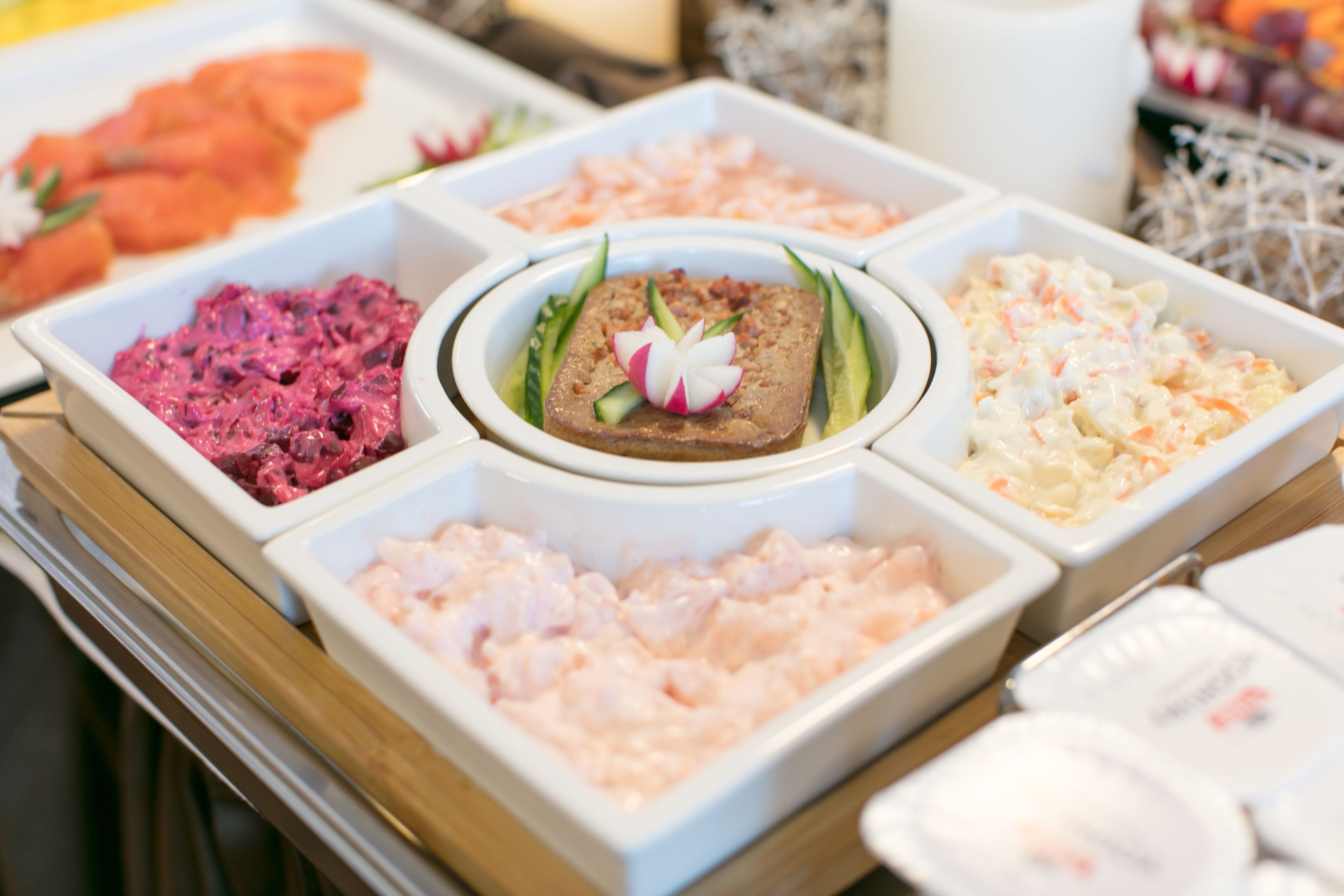 A buffet with various dishes including salmon, shrimp, and a central dish garnished with a flower.