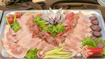 A tray of assorted meats and vegetables, including prosciutto, salami, and radishes, arranged on a metal tray.