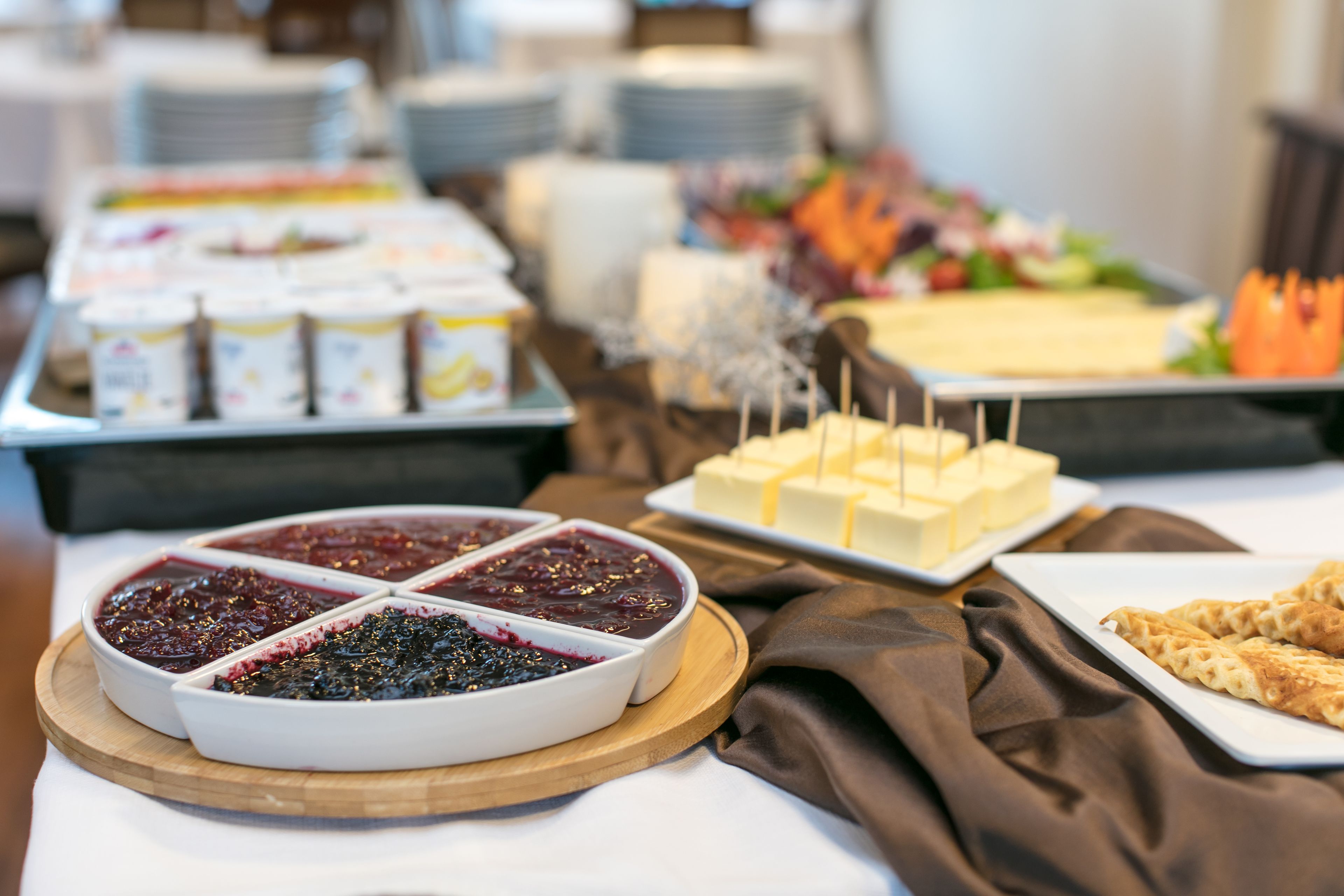 A buffet with various food items including a berry dessert, cheese, and bread.