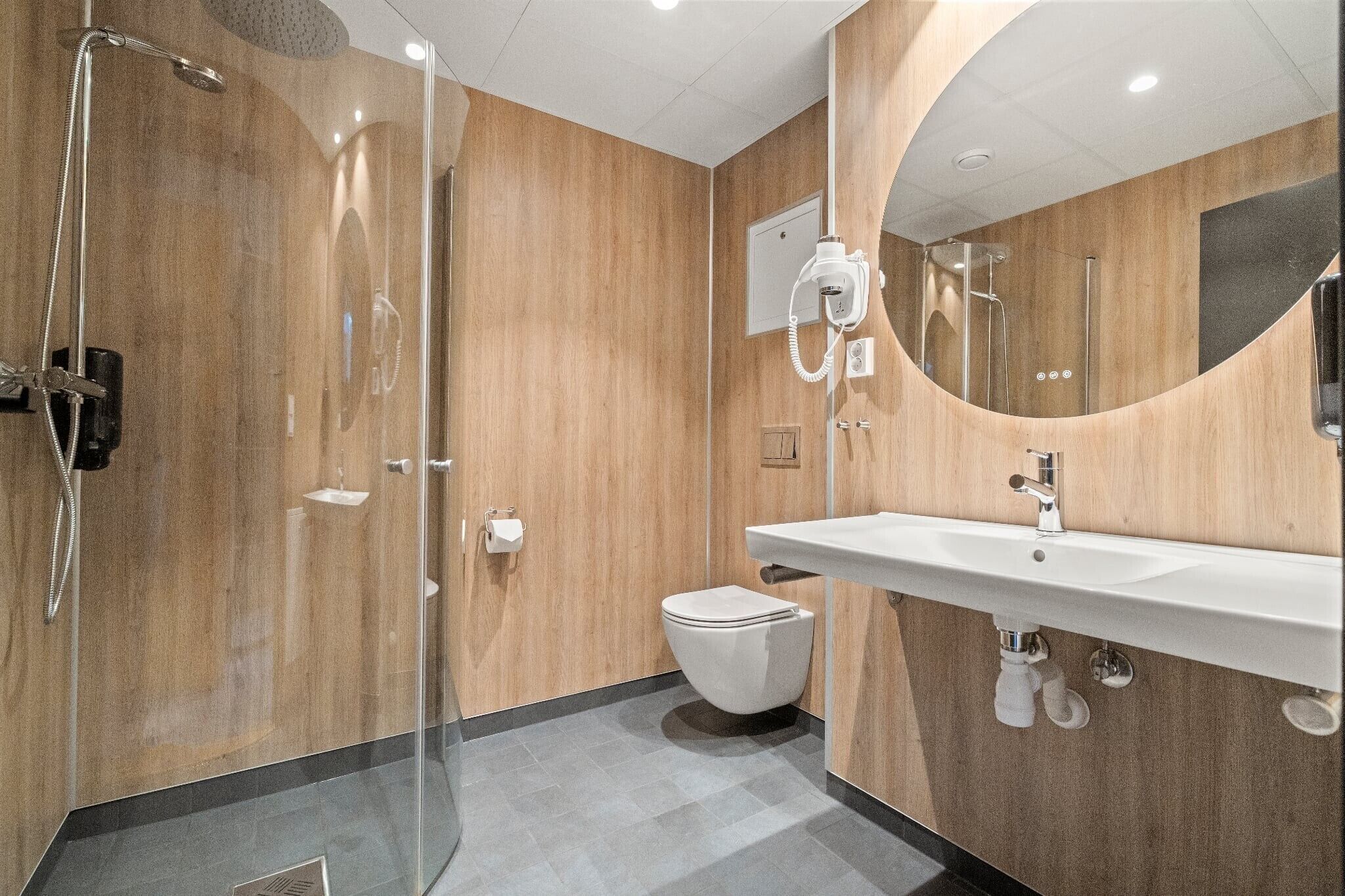Une salle de bain moderne avec une douche à parois de verre, un lavabo blanc et un grand miroir.