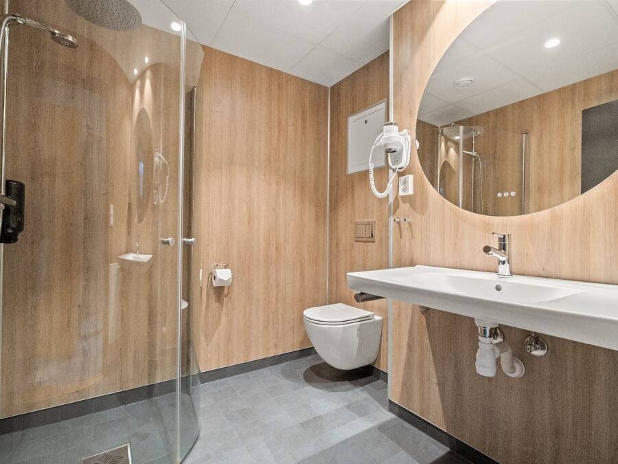 Une salle de bain moderne avec une douche à parois de verre, un lavabo blanc et un grand miroir.