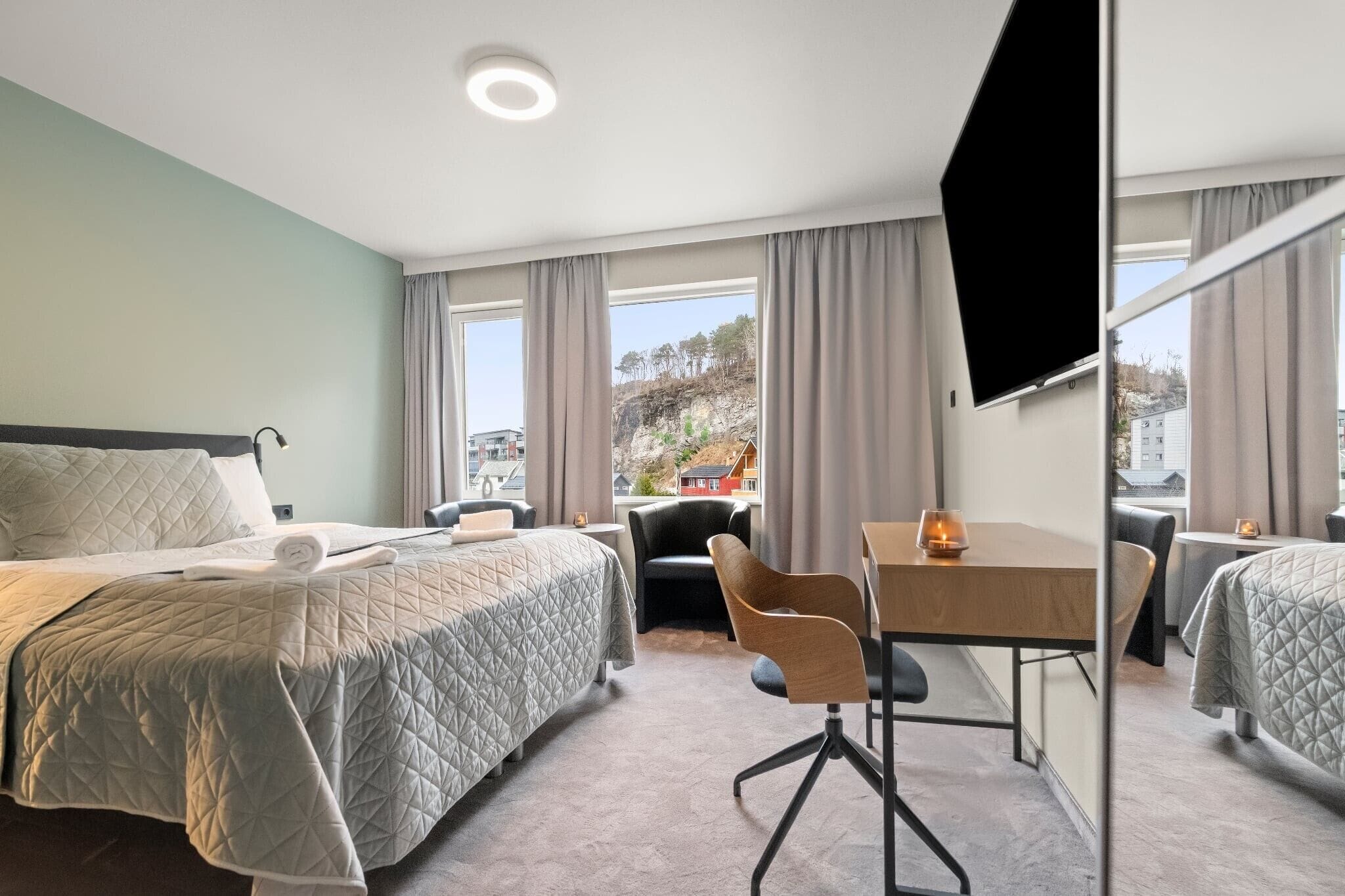 Une chambre d’hôtel avec un lit, un bureau, une chaise et un téléviseur.