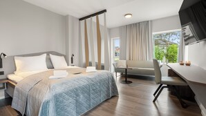 A modern hotel room with a large bed, a desk, and a chair. - Kinn Hotell Florø (Kinn)