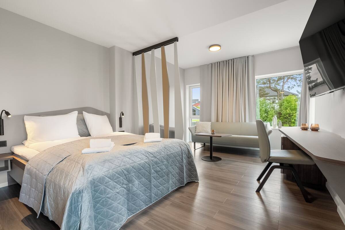 A modern hotel room with a large bed, a desk, and a chair.