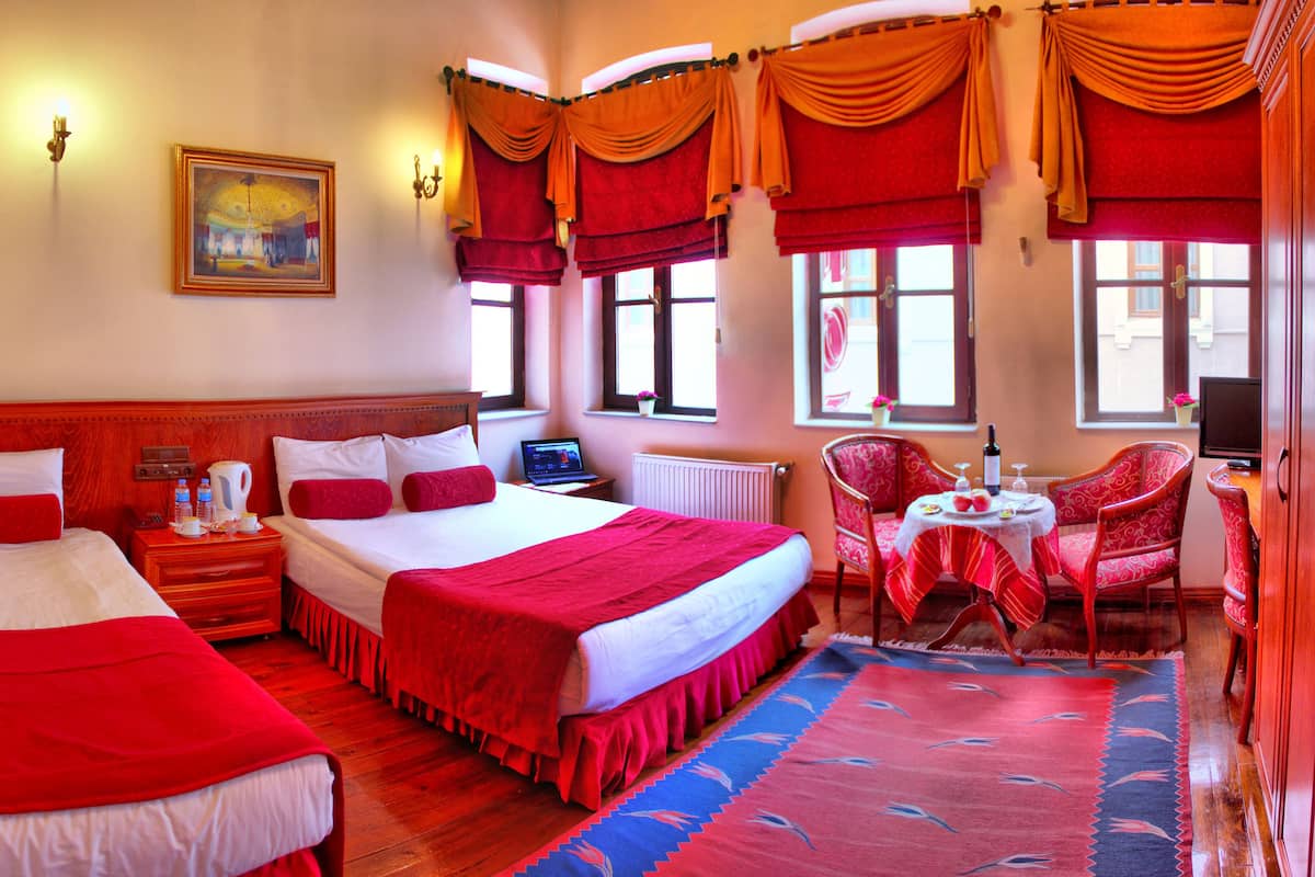 A hotel room with two beds, a dining area, and a TV.