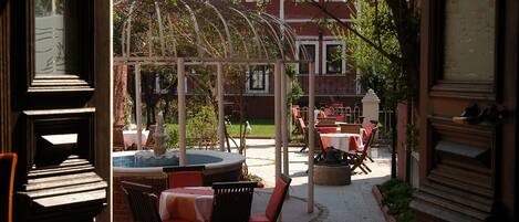 Un patio al aire libre con mesas, sillas, una bañera de hidromasaje y una pérgola.