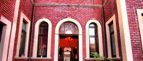 Un edificio de ladrillo rojo con ventanas arqueadas y una entrada central con una araña.