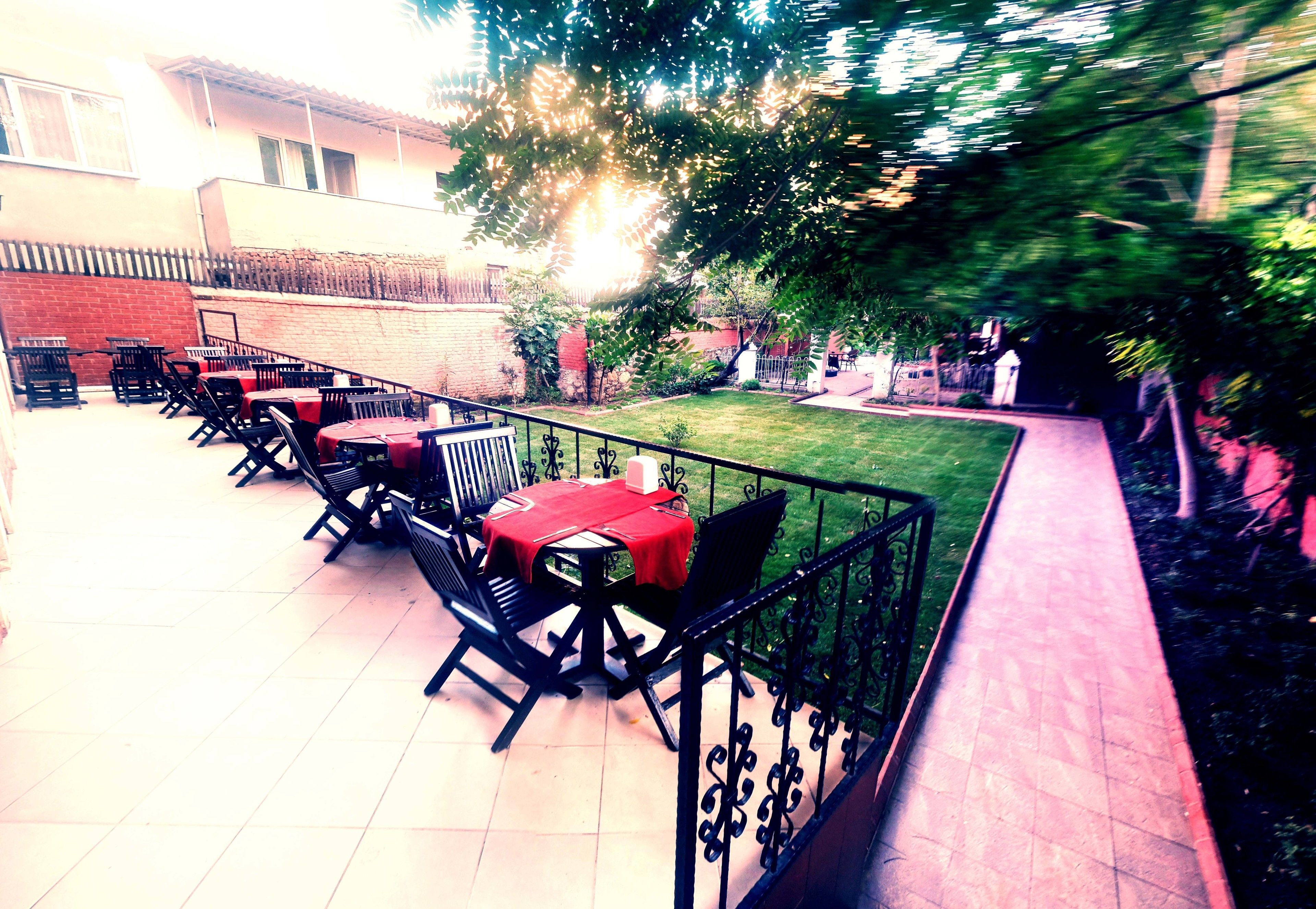 An outdoor patio with multiple tables and chairs, a brick wall, and a grassy area.