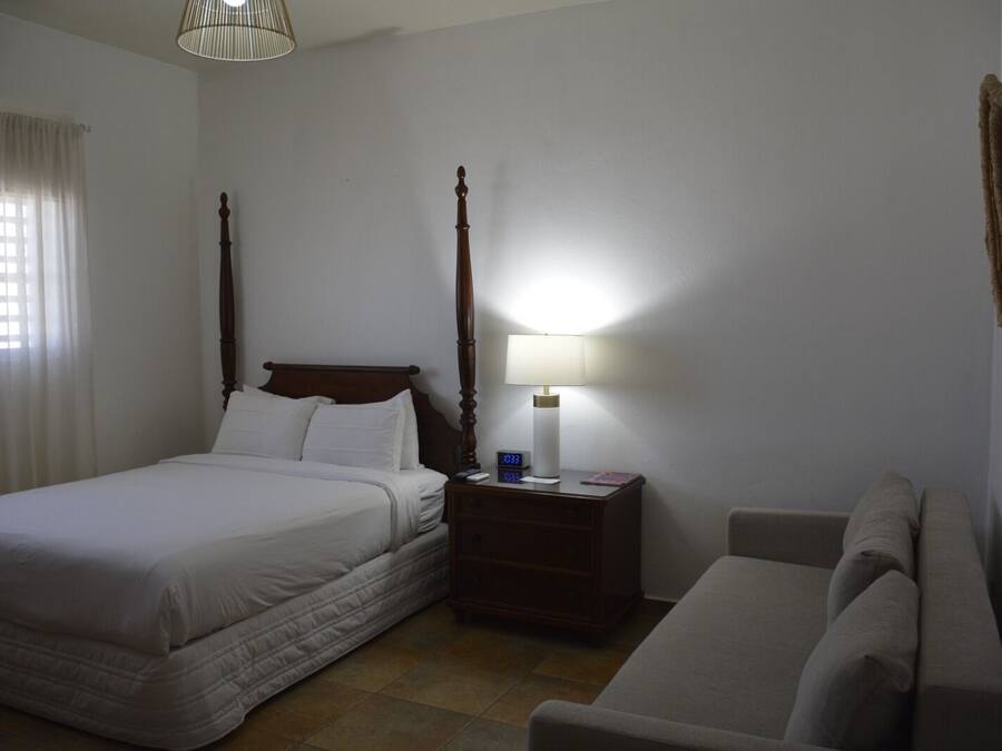 Une chambre à coucher avec un lit à baldaquin, une table de chevet avec une lampe et un canapé.